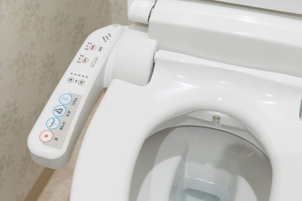 A high-tech Japanese bidet toilet with a control panel attached to the seat. The panel features various buttons for different functions, including water spray adjustments, bidet settings, and drying options. The sleek and modern design showcases the advanced technology commonly found in Japanese bathrooms.