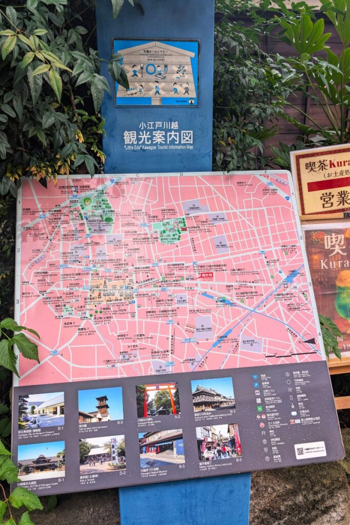 A tourist information board labeled “Little Edo Kawagoe Tourist Information Map” displays a detailed pink street map of the city with highlighted landmarks, icons, and walking routes. Below the map are photo thumbnails of key attractions like Toki no Kane, Kitain Temple, and Penny Candy Lane, with grid references for easy navigation.