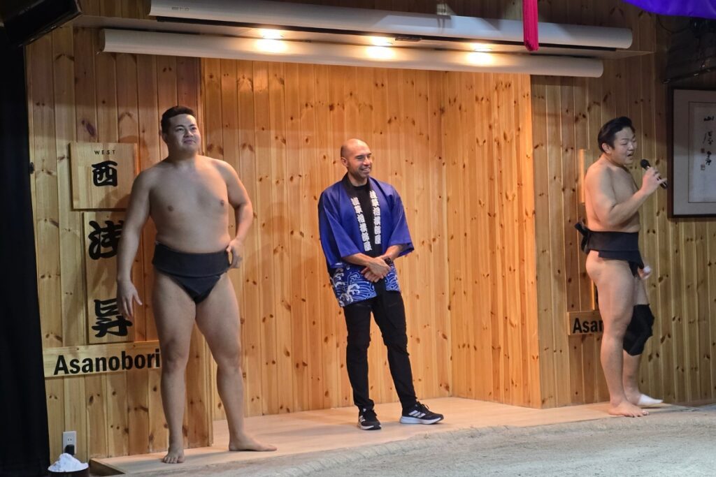 Wrestlers Asanobori and Asanokuma introduced by the MC on the sumo ring stage at Asakusa Sumo Club.