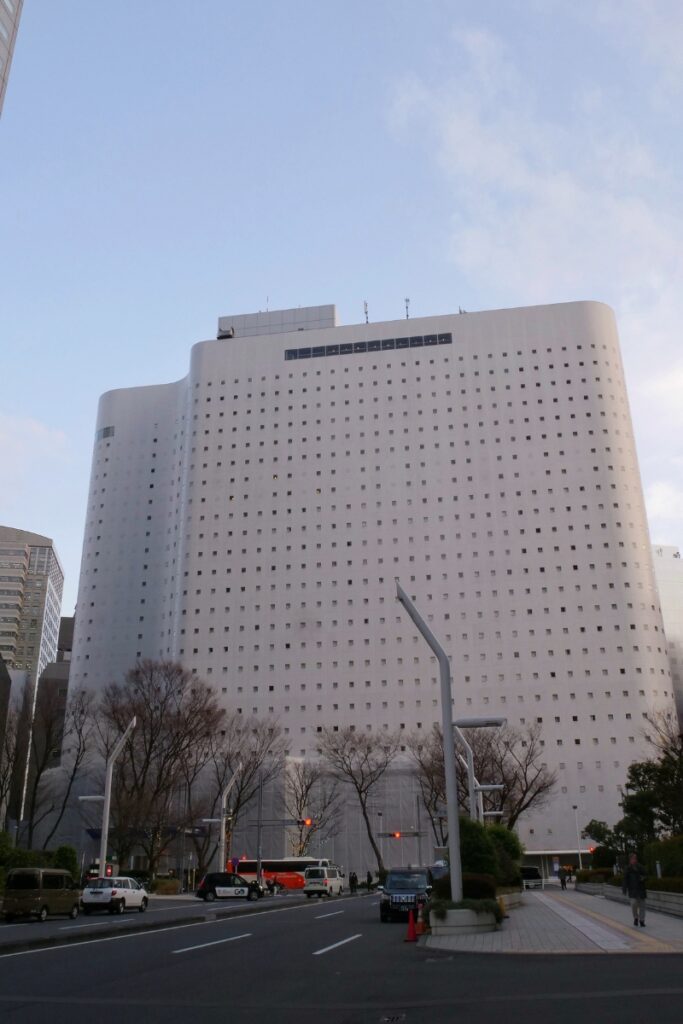 Shinjuku Washington Hotel distinctive curved white tower exterior viewed from the street at dusk.