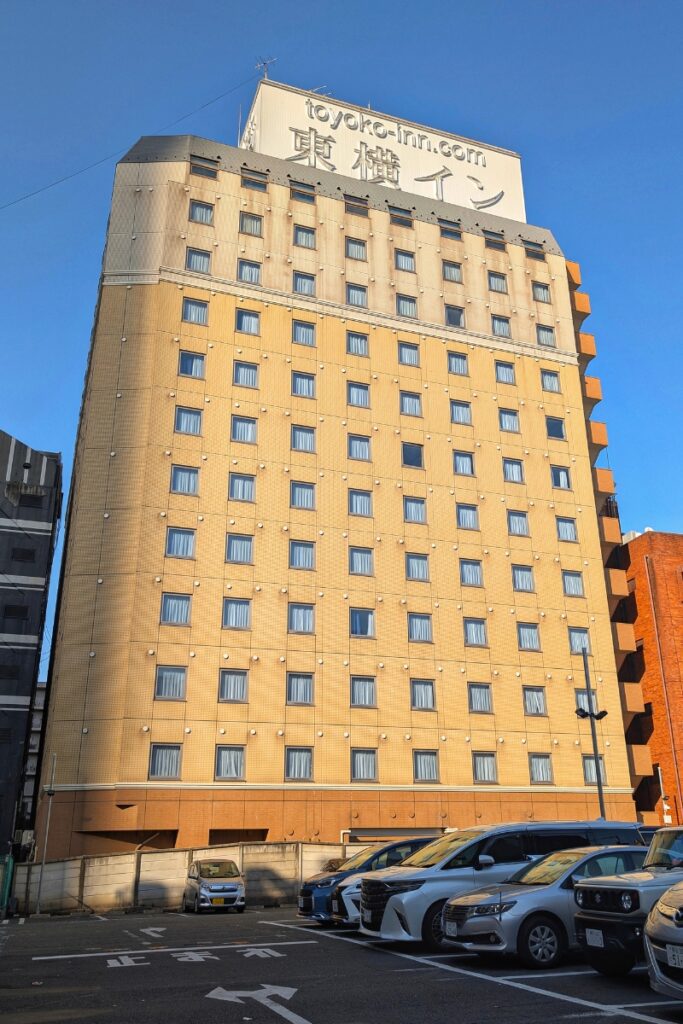 Toyoko Inn Shinjuku Kabukicho hotel exterior with large rooftop signage, viewed from the car park below.